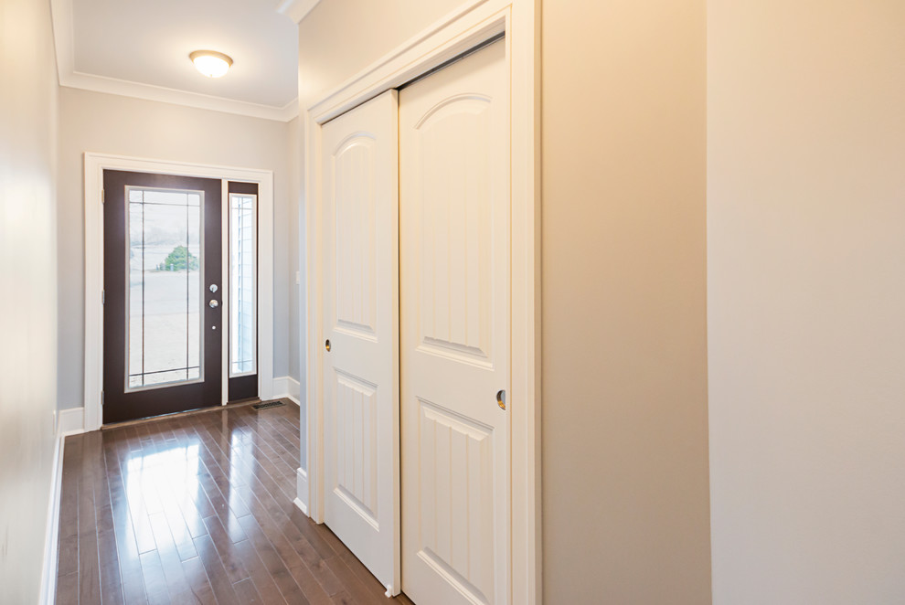 Imagen de hall de estilo americano de tamaño medio con paredes beige, suelo laminado, suelo marrón, puerta simple y puerta de vidrio