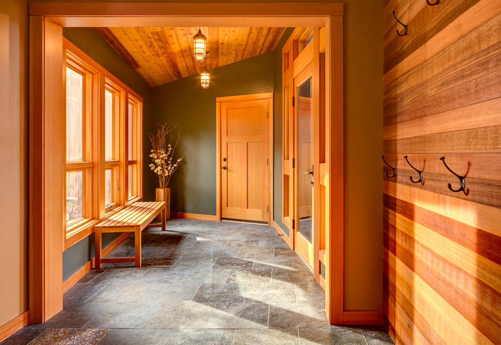 Cette photo montre une entrée craftsman de taille moyenne avec un mur multicolore, une porte simple, une porte en bois brun, un vestiaire et un sol gris.