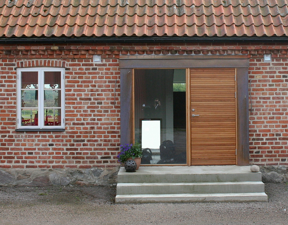Ejemplo de puerta principal campestre de tamaño medio con suelo de cemento, puerta de madera clara y puerta simple