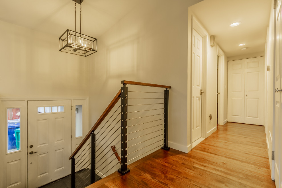 Bild på en funkis entré, med beige väggar, mellanmörkt trägolv, en vit dörr och brunt golv