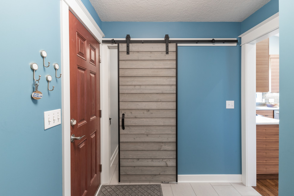 Foto de puerta principal minimalista pequeña con paredes azules, suelo de baldosas de porcelana, puerta simple, puerta de madera en tonos medios y suelo gris
