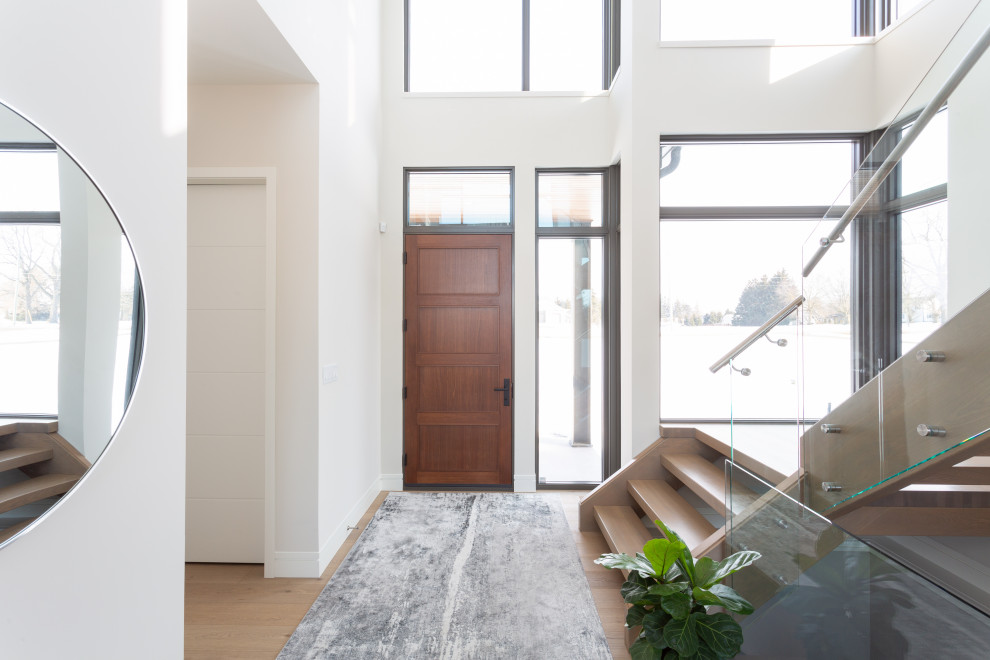 Contemporary foyer in Toronto with white walls, medium hardwood flooring, a single front door, a medium wood front door and brown floors.