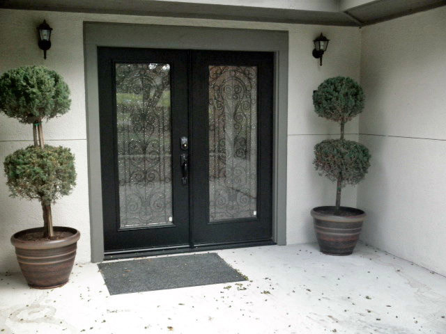 This is an example of a large contemporary front door in Los Angeles with grey walls, concrete flooring, a double front door and a black front door.