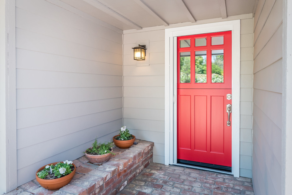 Réalisation d'une porte d'entrée craftsman de taille moyenne avec un mur gris, un sol en brique, une porte hollandaise et une porte rouge.