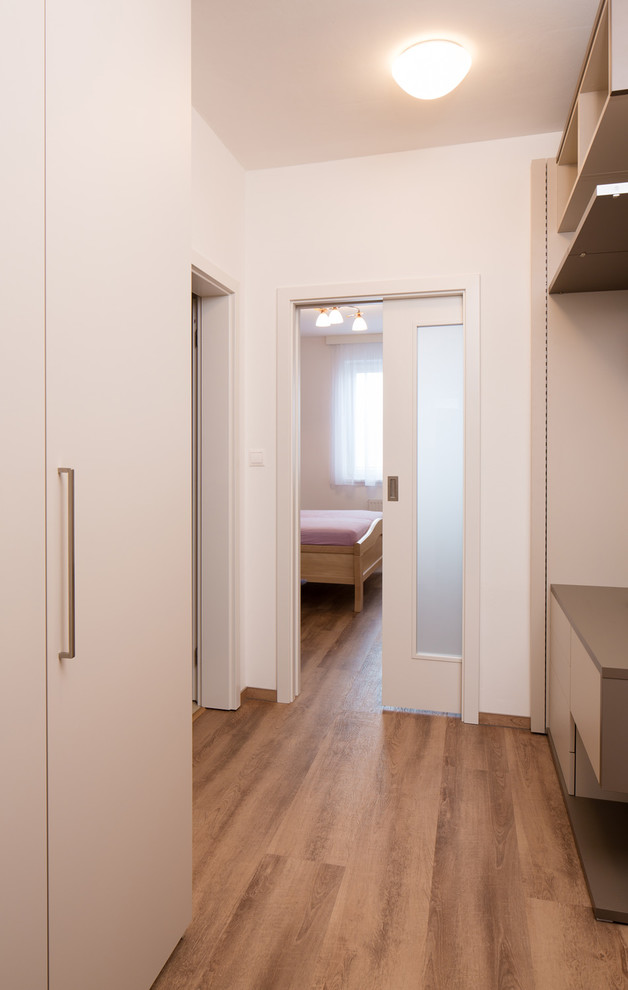 Kleine Moderne Haustür mit weißer Wandfarbe, Sperrholzboden, Einzeltür, weißer Haustür und braunem Boden in Sonstige