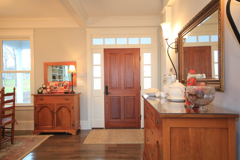 Modelo de puerta principal campestre de tamaño medio con paredes grises, suelo de madera oscura, puerta simple y puerta de madera en tonos medios