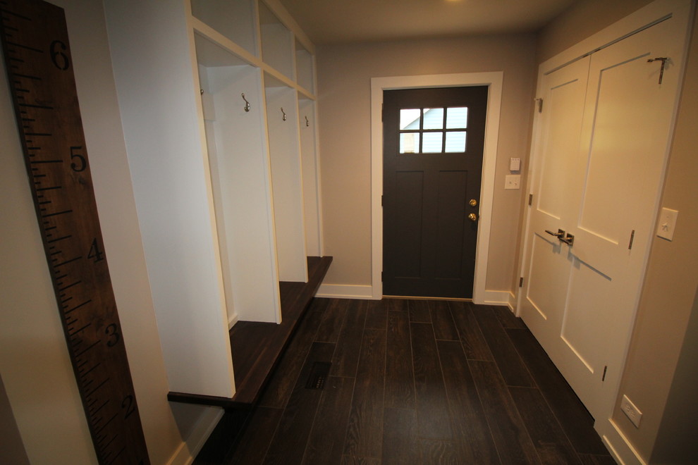 На фото: узкая прихожая среднего размера в стиле неоклассика (современная классика) с серыми стенами, темным паркетным полом, поворотной входной дверью и входной дверью из темного дерева