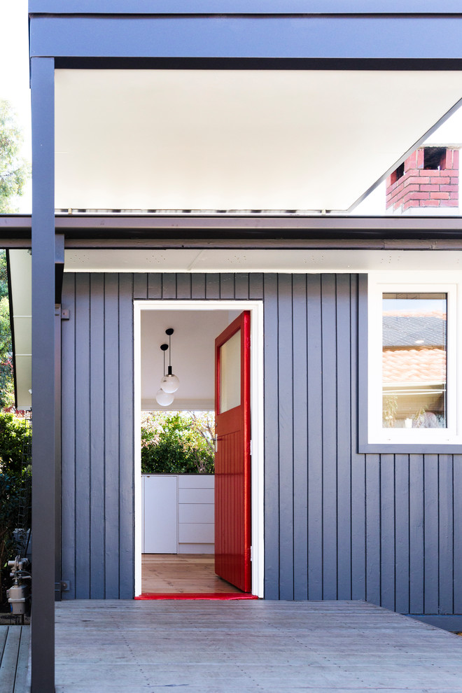 Exempel på en liten modern ingång och ytterdörr, med mellanmörkt trägolv, en enkeldörr, en röd dörr, blå väggar och brunt golv