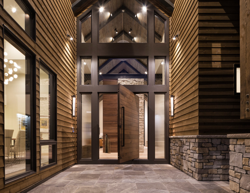 Cette image montre une très grande porte d'entrée minimaliste avec une porte pivot, une porte en bois foncé, parquet clair et un sol marron.