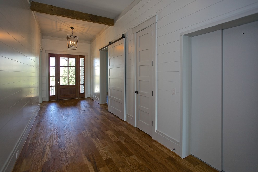 Diseño de hall marinero con paredes blancas, suelo de madera en tonos medios, puerta simple y puerta de madera en tonos medios