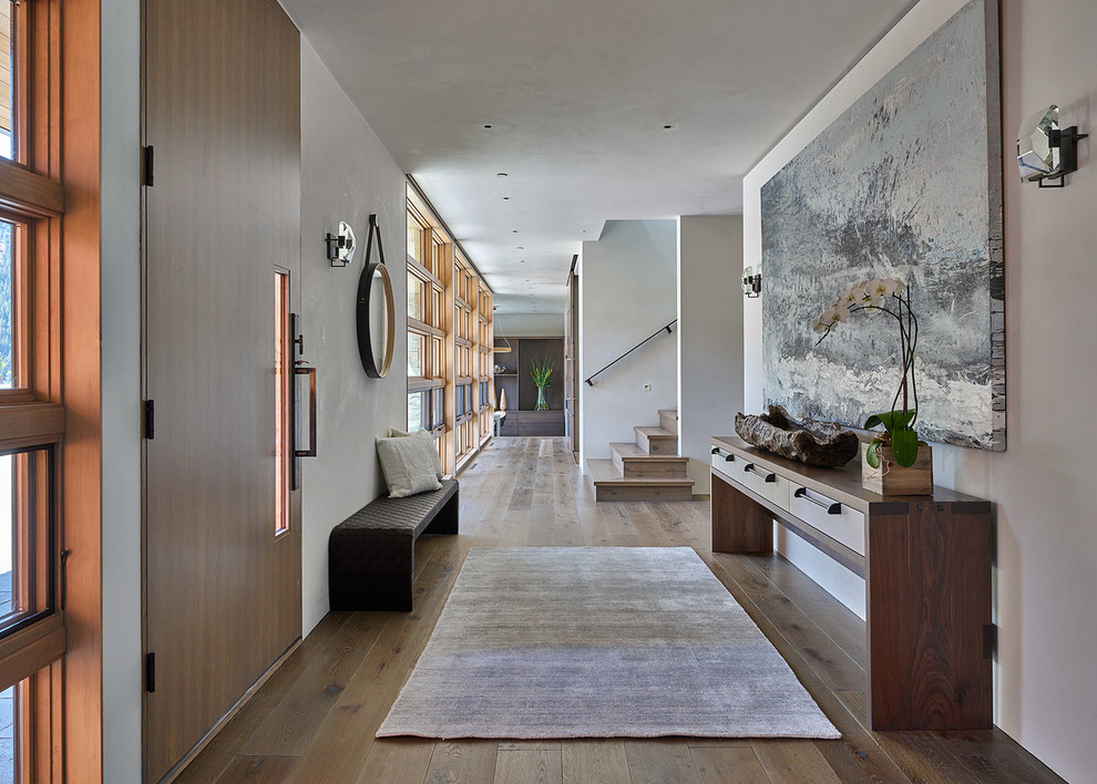 Idées déco pour une entrée contemporaine avec un couloir, un mur blanc, un sol en bois brun, une porte simple et une porte en bois brun.