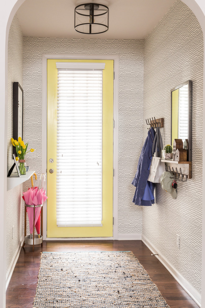Foto på en mellanstor funkis foajé, med gula väggar, mörkt trägolv, en enkeldörr, en gul dörr och brunt golv