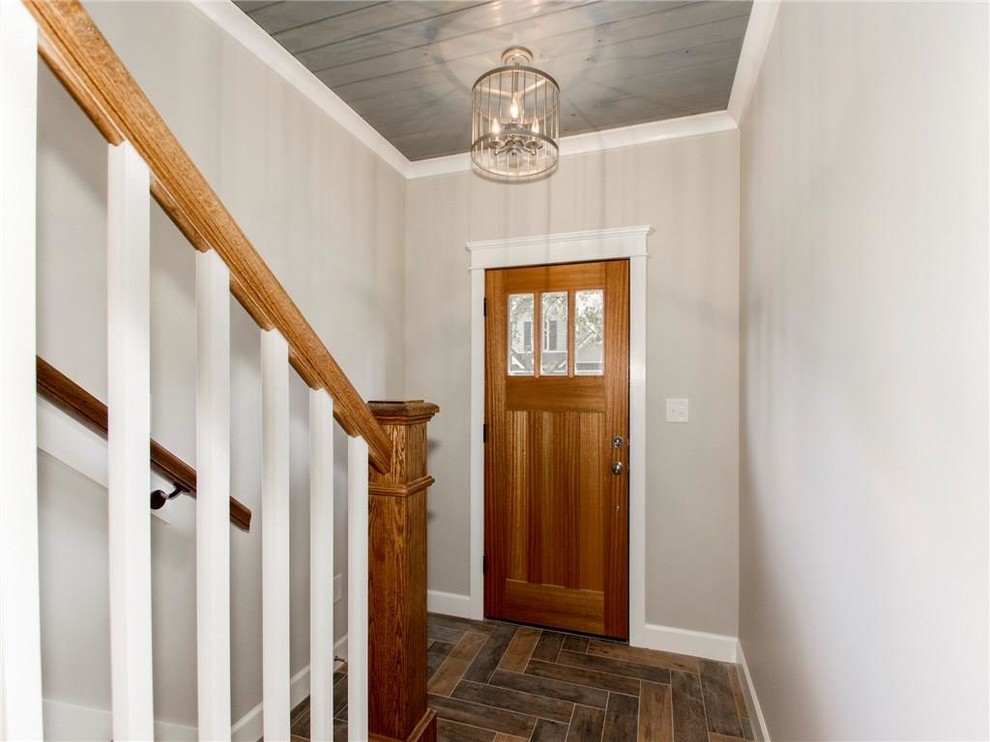 Cette image montre une petite entrée craftsman avec un couloir, un mur beige, un sol en bois brun, une porte simple, une porte en bois brun et un sol marron.