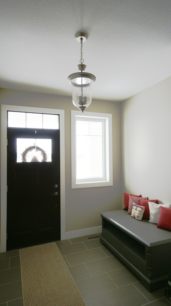 This is an example of a medium sized contemporary vestibule in Calgary with beige walls, a single front door and a dark wood front door.