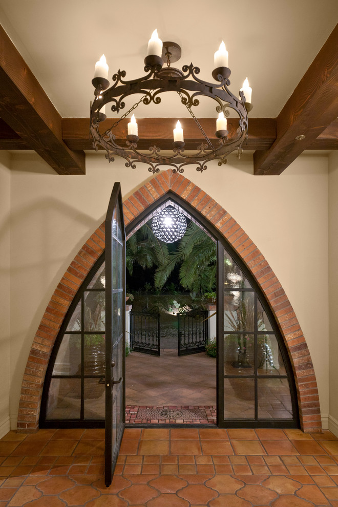 他の地域にある地中海スタイルのおしゃれな玄関ドア (ベージュの壁、テラコッタタイルの床、ガラスドア) の写真