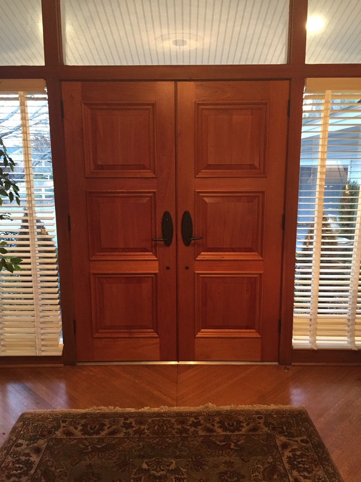 Cette photo montre une porte d'entrée moderne avec un sol en bois brun, une porte double et une porte en bois brun.