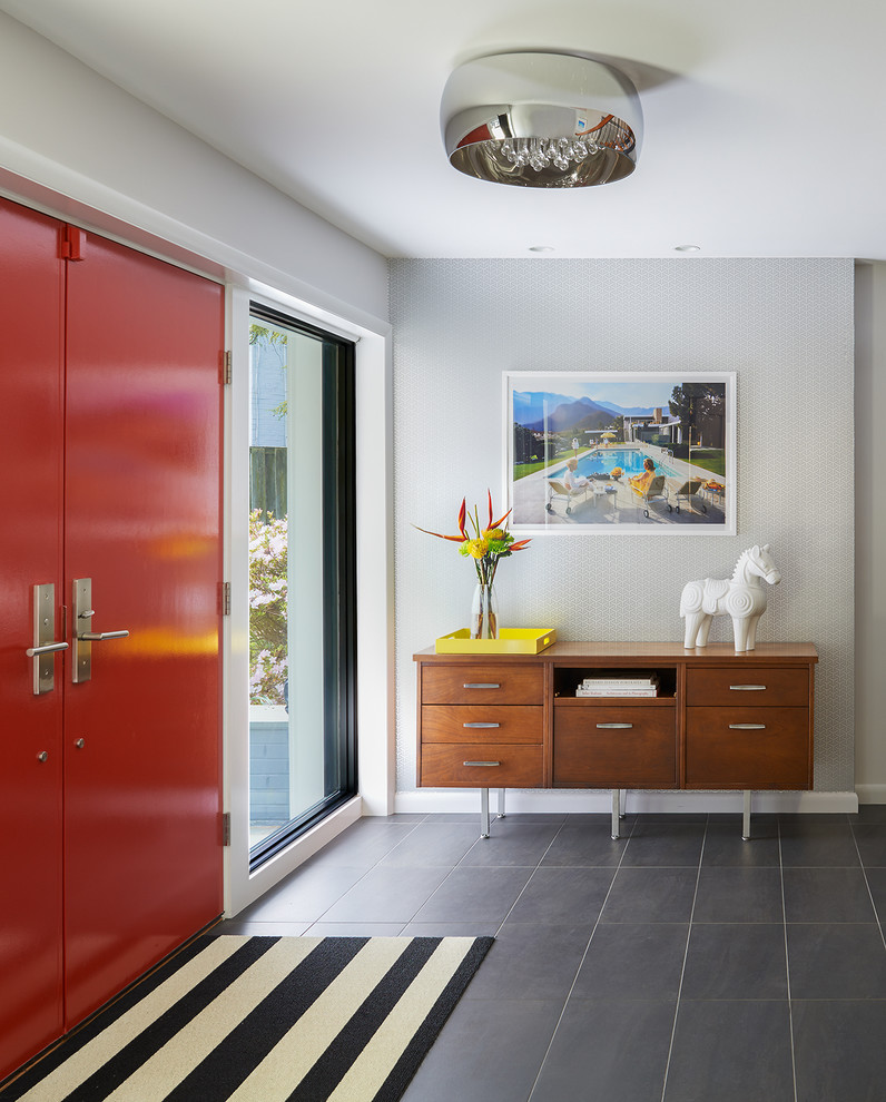 50 tals inredning av en stor foajé, med en dubbeldörr, grå väggar, skiffergolv, en röd dörr och grått golv