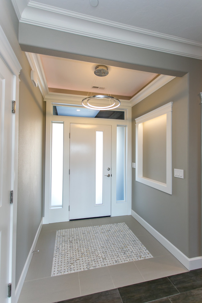 На фото: маленькая входная дверь в стиле неоклассика (современная классика) с серыми стенами, полом из керамогранита, одностворчатой входной дверью, белой входной дверью и серым полом для на участке и в саду с