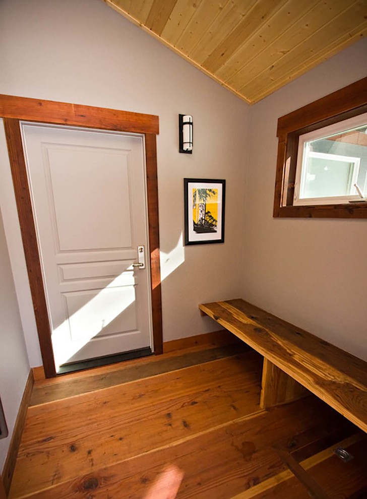 Bild på ett mellanstort rustikt kapprum, med vita väggar, mellanmörkt trägolv, en pivotdörr och en vit dörr