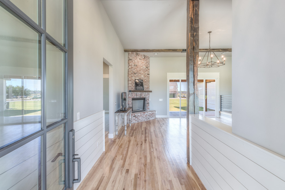 Idee per un ingresso country di medie dimensioni con pareti grigie, pavimento in legno massello medio, una porta singola, una porta bianca e pavimento marrone