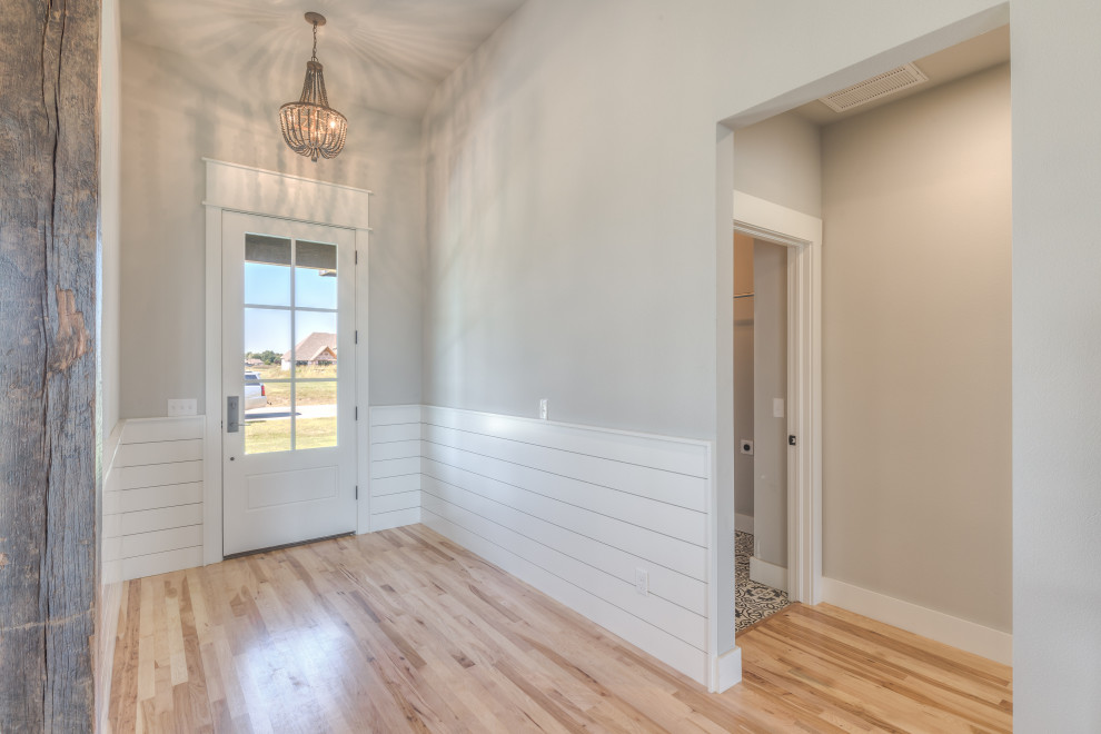 他の地域にある中くらいなカントリー風のおしゃれな玄関ロビー (グレーの壁、無垢フローリング、白いドア、茶色い床) の写真