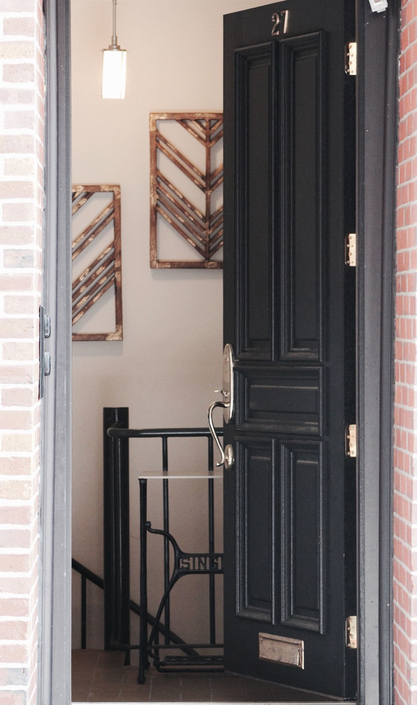 На фото: входная дверь в классическом стиле с бежевыми стенами, кирпичным полом, одностворчатой входной дверью, черной входной дверью и красным полом