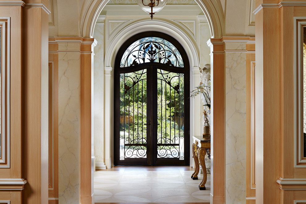 На фото: входная дверь в средиземноморском стиле с бежевыми стенами, двустворчатой входной дверью, черной входной дверью, бежевым полом и гранитным полом