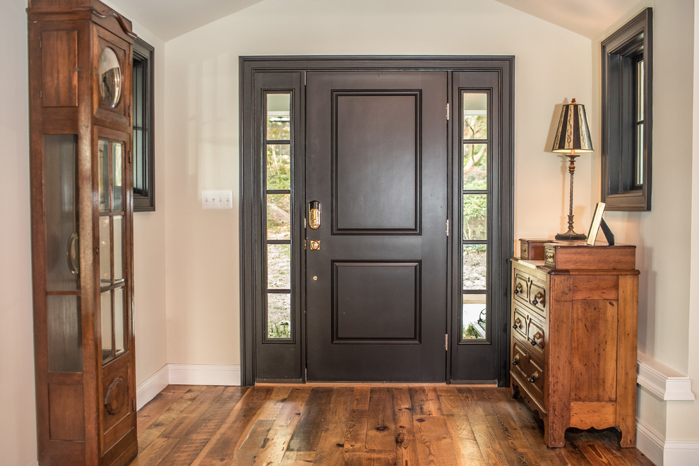 Foto de distribuidor rústico de tamaño medio con suelo de madera en tonos medios, puerta simple, puerta negra, paredes beige y suelo marrón