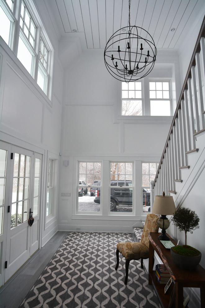 Стильный дизайн: огромное фойе в стиле кантри с белыми стенами, деревянным полом, одностворчатой входной дверью и белой входной дверью - последний тренд