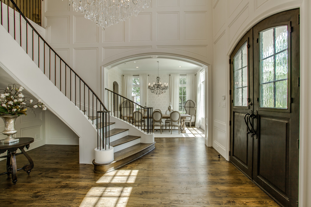 ダラスにあるラグジュアリーな巨大なトラディショナルスタイルのおしゃれな玄関ロビー (白い壁、無垢フローリング、濃色木目調のドア) の写真