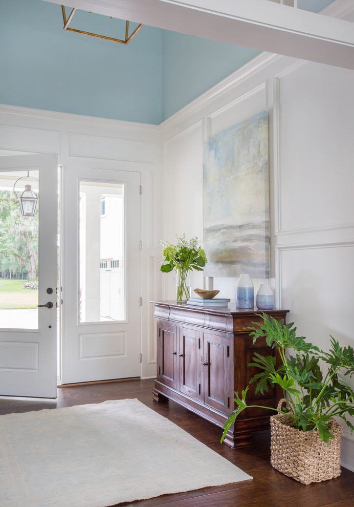 Bild på en vintage ingång och ytterdörr, med blå väggar, mellanmörkt trägolv, en enkeldörr, en vit dörr och brunt golv