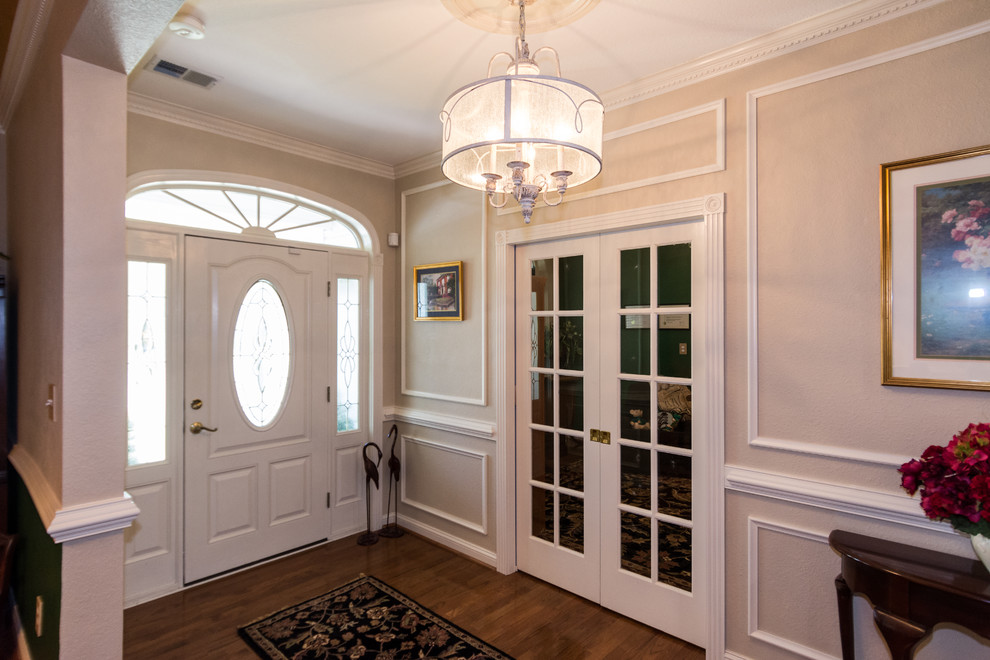 Aménagement d'un hall d'entrée classique de taille moyenne avec un mur beige, un sol en bois brun et une porte blanche.