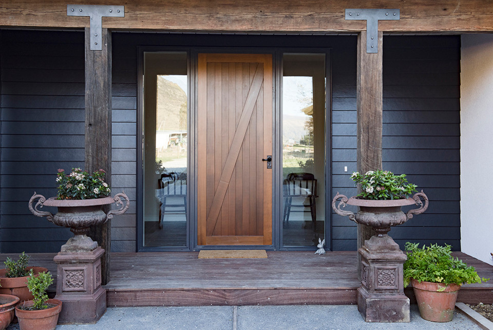 Aménagement d'une grande porte d'entrée campagne avec un mur bleu, parquet foncé, une porte simple, une porte en bois brun et un sol marron.