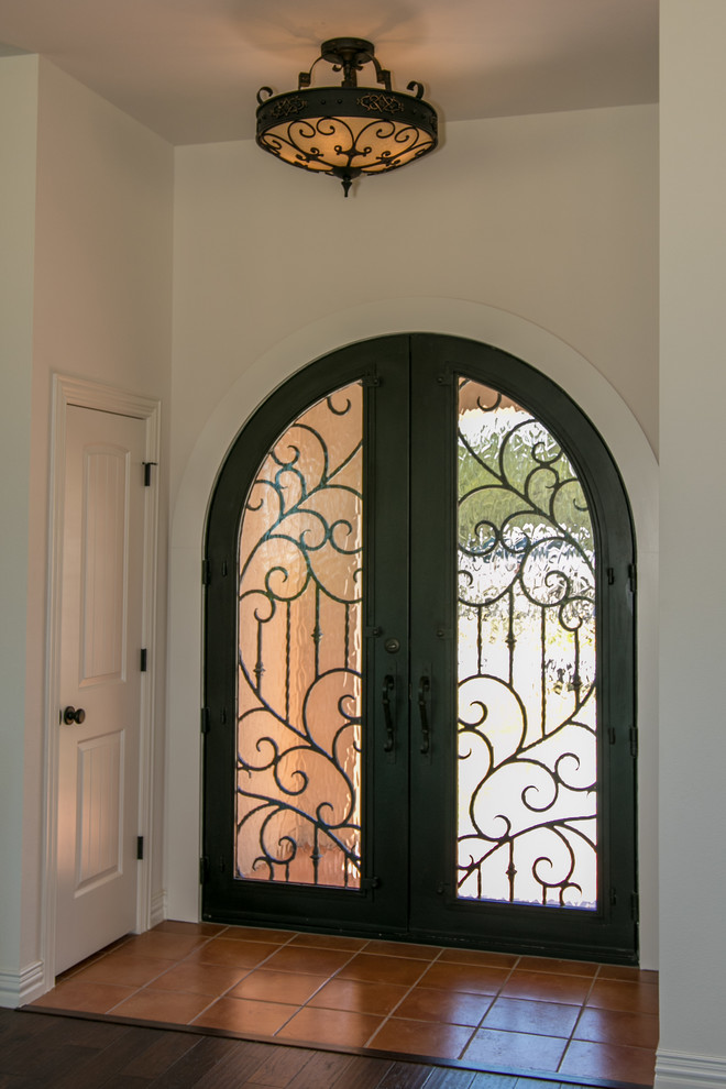 Ejemplo de puerta principal de estilo americano grande con paredes blancas, suelo de baldosas de terracota, puerta doble, puerta de vidrio y suelo naranja