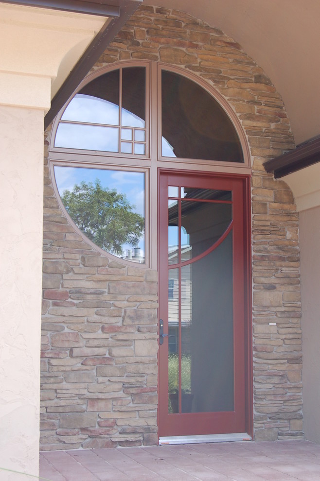 This is an example of a medium sized front door in Other with a single front door, a glass front door, beige walls and brick flooring.