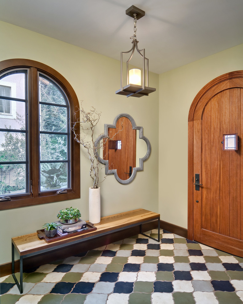 サンフランシスコにある小さな地中海スタイルのおしゃれな玄関ドア (黄色い壁、セラミックタイルの床、木目調のドア) の写真