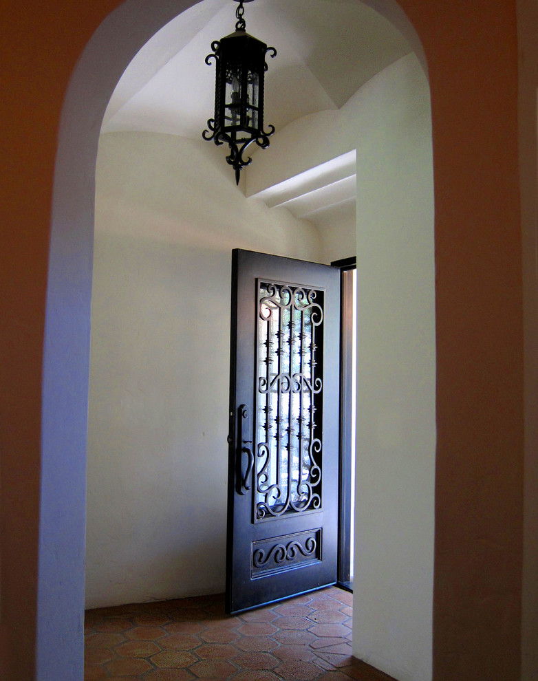 サンタバーバラにある高級な小さな地中海スタイルのおしゃれな玄関ロビー (白い壁、テラコッタタイルの床、金属製ドア、赤い床) の写真