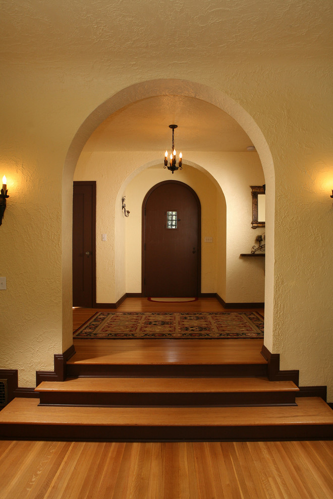 Immagine di un ingresso mediterraneo con pareti beige, pavimento in legno massello medio, una porta singola e una porta in legno scuro