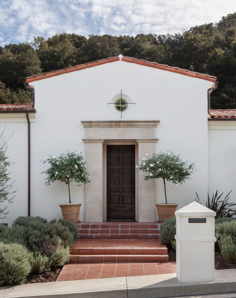 Große Mediterrane Haustür mit weißer Wandfarbe, Terrakottaboden, Einzeltür und dunkler Holzhaustür in Los Angeles