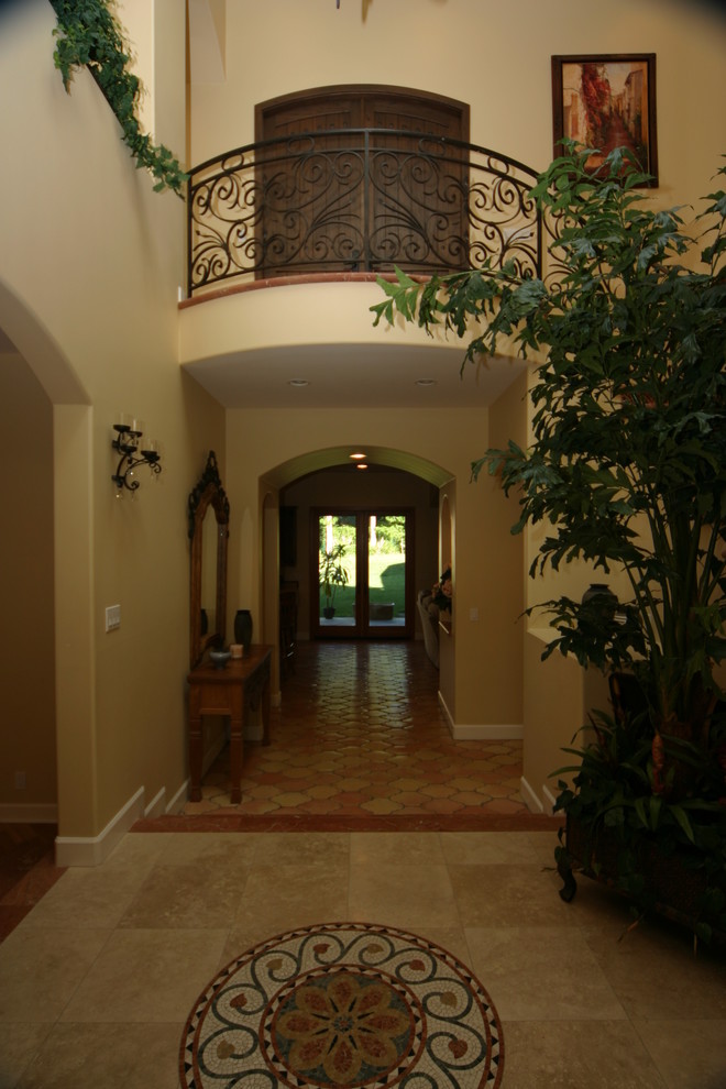 Mid-sized tuscan travertine floor entryway photo in Orange County with beige walls and a dark wood front door