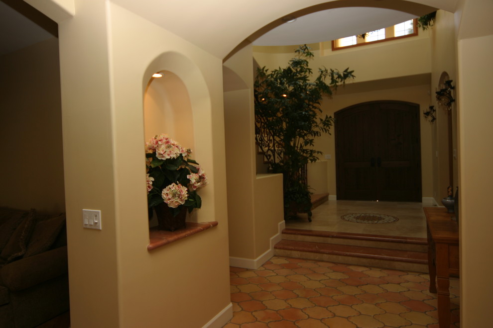 Mid-sized tuscan travertine floor entryway photo in Orange County with beige walls and a dark wood front door