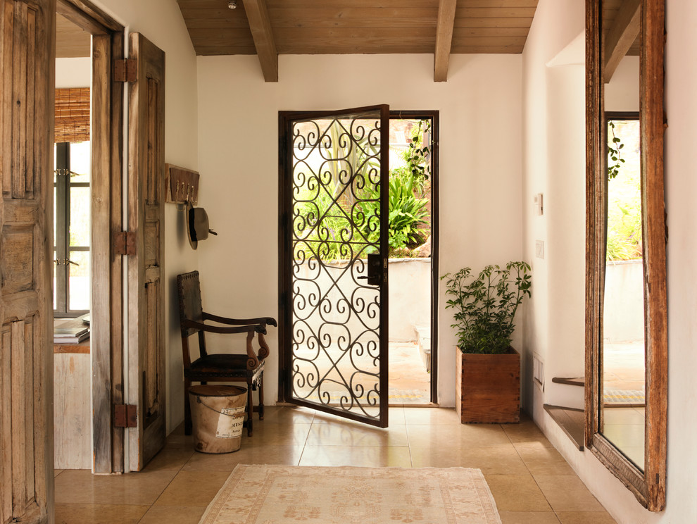 На фото: фойе в средиземноморском стиле с белыми стенами и одностворчатой входной дверью с