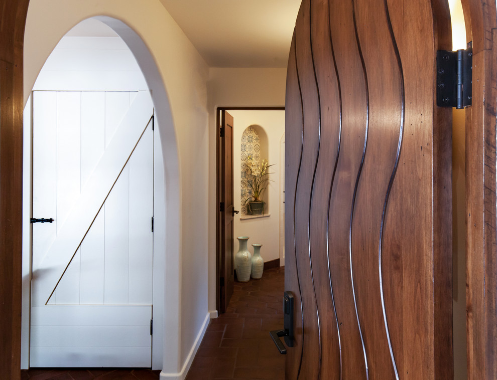 Esempio di un corridoio mediterraneo di medie dimensioni con pareti bianche, pavimento in terracotta, una porta a due ante e una porta in legno bruno
