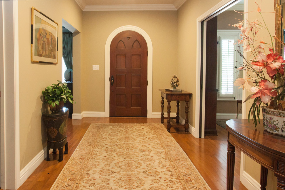 Imagen de puerta principal mediterránea grande con paredes beige, suelo de madera en tonos medios, puerta simple, puerta de madera oscura y suelo marrón
