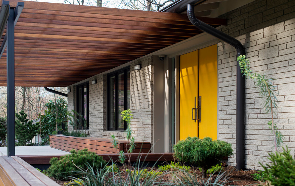 Design ideas for a midcentury front door in Raleigh with beige walls, concrete flooring, a double front door, a yellow front door and grey floors.