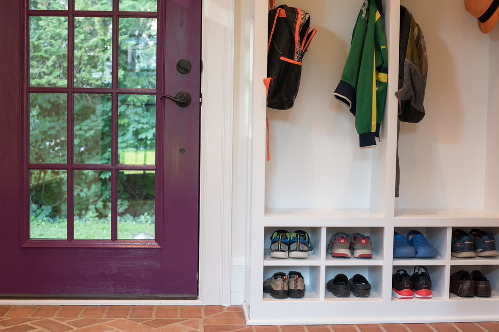 На фото: тамбур со шкафом для обуви в классическом стиле с белыми стенами, кирпичным полом, одностворчатой входной дверью, фиолетовой входной дверью и красным полом