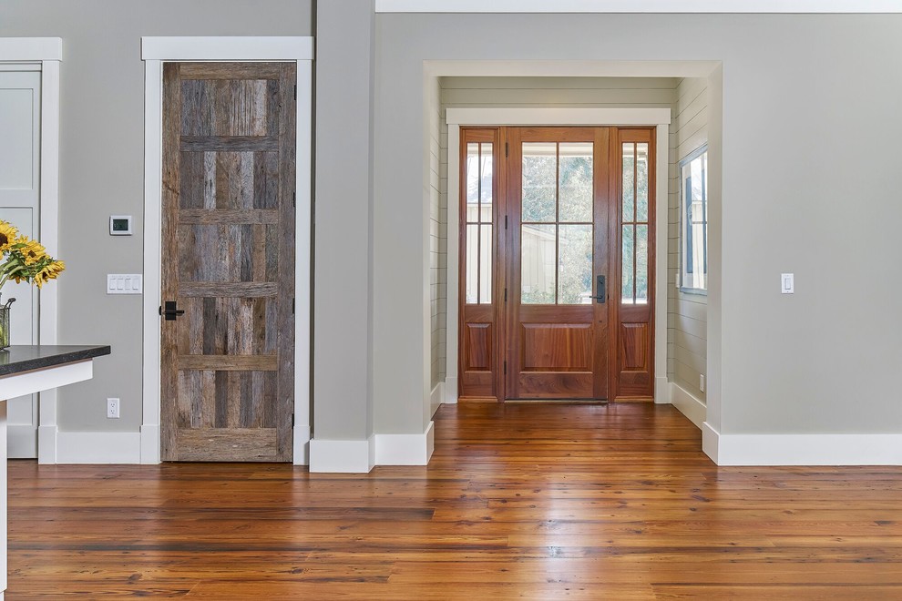 Cette photo montre un hall d'entrée chic de taille moyenne avec un mur gris, un sol en bois brun, une porte simple et une porte en bois brun.