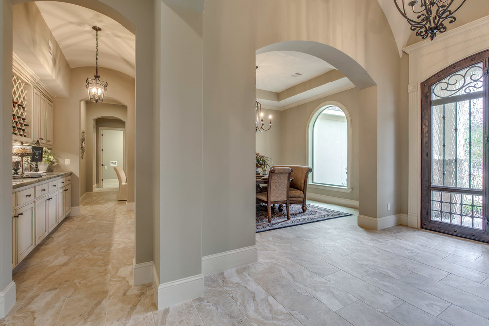 Example of a large tuscan ceramic tile and beige floor entryway design in Houston with beige walls and a metal front door