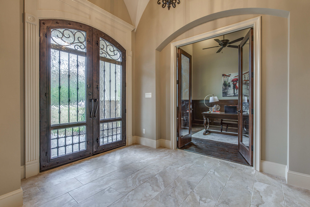 This is an example of a large mediterranean foyer in Houston with beige walls, ceramic flooring, a double front door, a metal front door and beige floors.