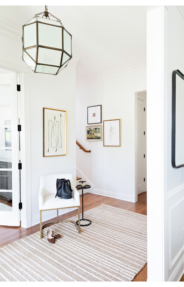 Immagine di un ingresso chic di medie dimensioni con pareti bianche, pavimento in legno massello medio, una porta singola, una porta in legno chiaro e pavimento marrone